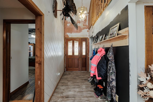 mudroom with wood walls, a notable chandelier, and wood finished floors