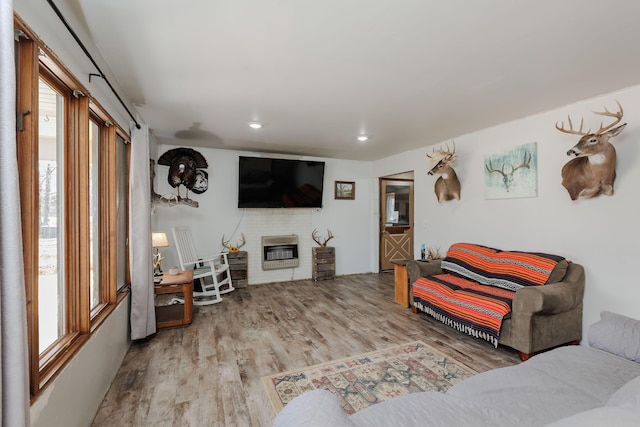 living room featuring a brick fireplace, recessed lighting, heating unit, and wood finished floors