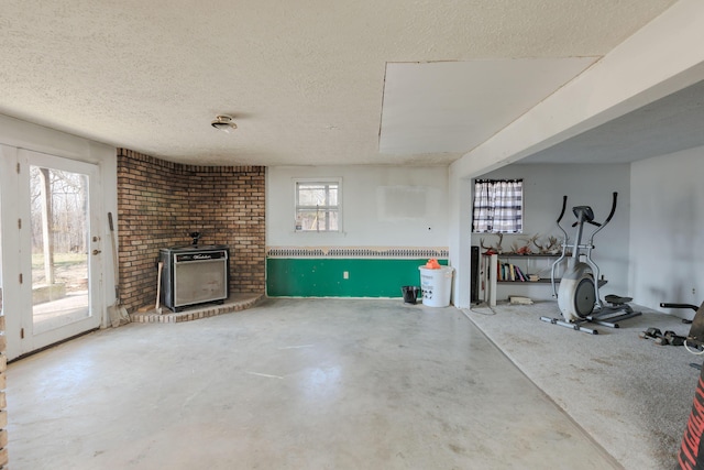 interior space featuring a textured ceiling, concrete flooring, a brick fireplace, and heating unit
