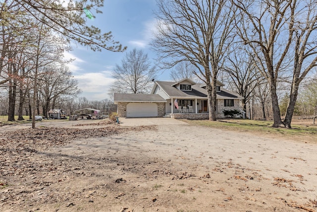 view of front of home with a porch, a garage, stone siding, and driveway
