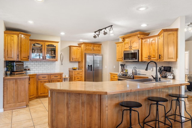 kitchen featuring a sink, light countertops, appliances with stainless steel finishes, a breakfast bar, and a peninsula