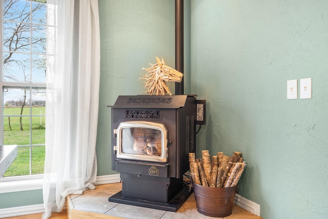 details with a wood stove, a textured wall, and baseboards