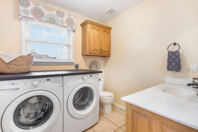 laundry area with visible vents, light tile patterned floors, a sink, laundry area, and washing machine and clothes dryer