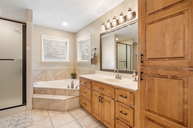 full bath with a textured ceiling, vanity, tile patterned flooring, a stall shower, and a garden tub