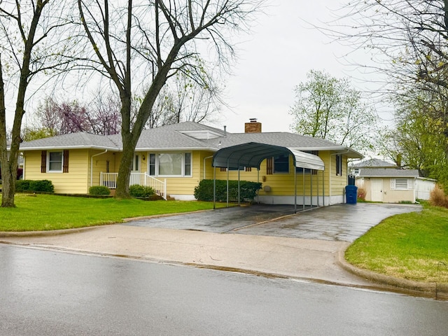 single story home with a detached carport, a chimney, aphalt driveway, and a front yard