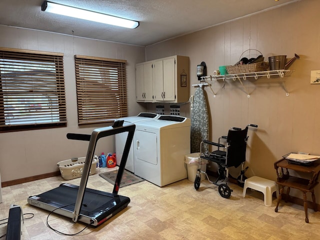 laundry room with cabinet space, washer and clothes dryer, light floors, and a textured ceiling