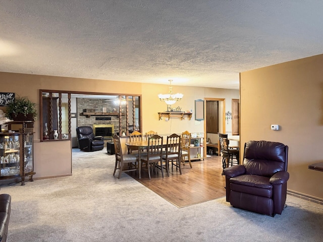 carpeted dining space featuring a chandelier, a fireplace, a textured ceiling, and baseboards