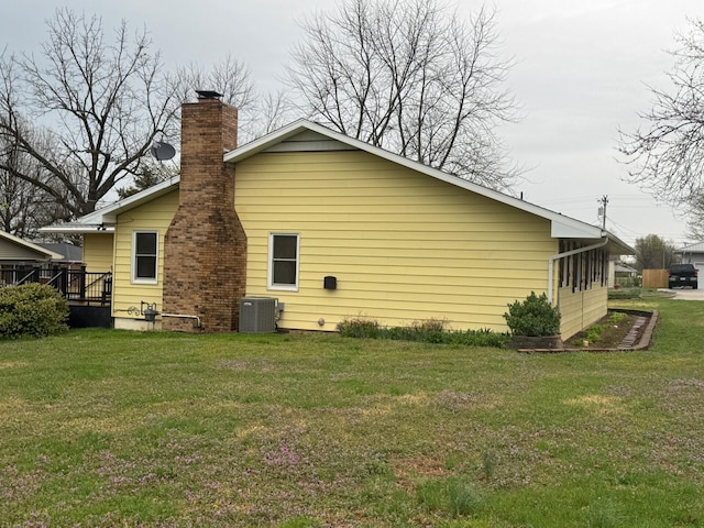 exterior space featuring cooling unit, a chimney, and a lawn