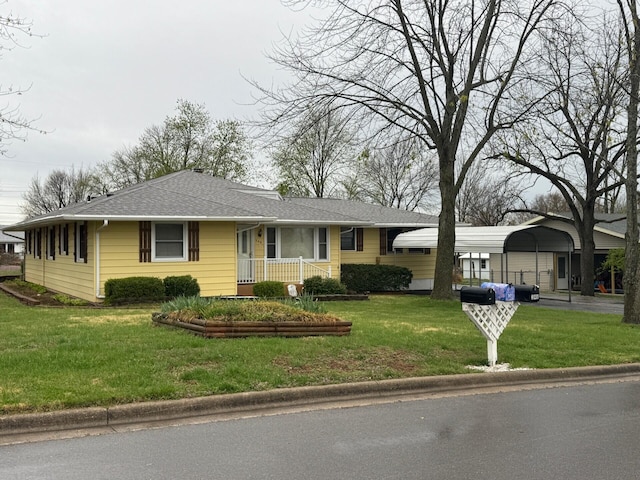 view of front of property with a front yard, a shingled roof, and a carport