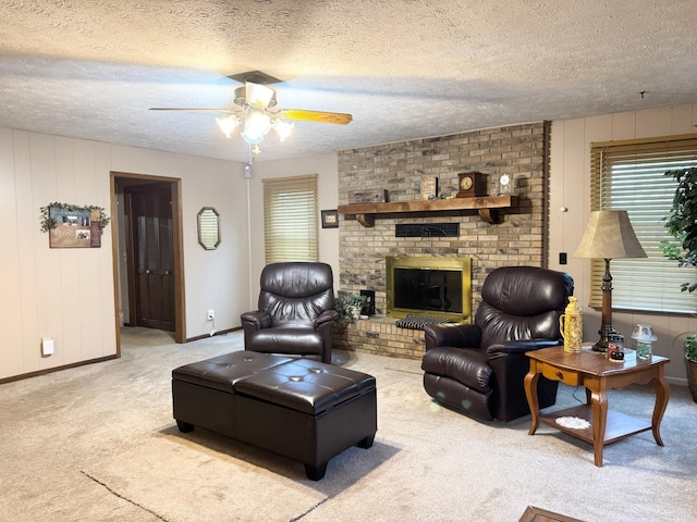 living room featuring a textured ceiling, ceiling fan, a fireplace, and carpet flooring