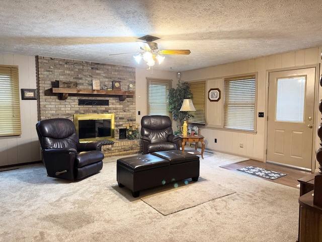 living room with a fireplace, ceiling fan, a textured ceiling, and carpet floors