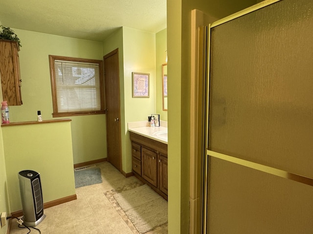 bathroom featuring a shower with door, tile patterned floors, vanity, and baseboards
