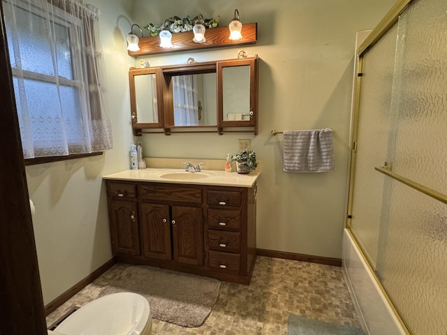 bathroom featuring toilet, baseboards, vanity, and bath / shower combo with glass door