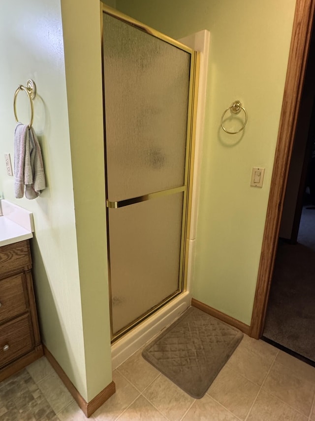 full bathroom with tile patterned floors, a shower stall, vanity, and baseboards