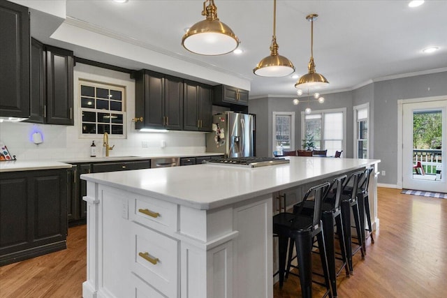 2111 Sycamore Dr, West Plains, MO 65775 - kitchen with light countertops, crown molding, light wood finished floors, stainless steel appliances, and a kitchen island
