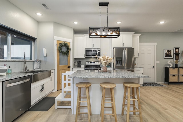 1798 E 328th Rd, Bolivar, MO 65613 - kitchen featuring appliances with stainless steel finishes, light wood finished floors, a sink, and a breakfast bar