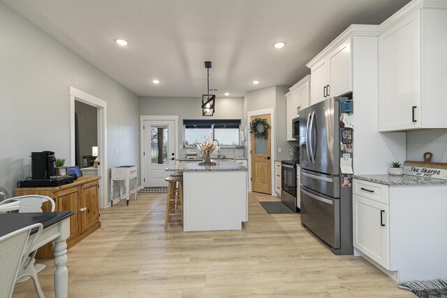 1798 E 328th Rd, Bolivar, MO 65613 - kitchen with light stone counters, a center island, white cabinetry, light wood-style floors, and appliances with stainless steel finishes
