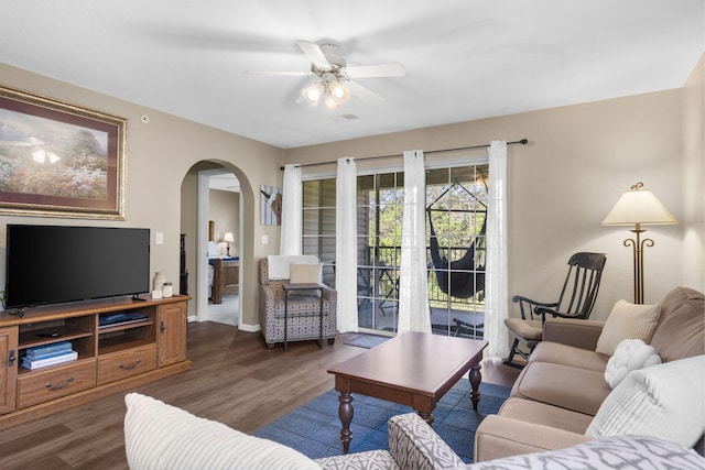 living area featuring visible vents, ceiling fan, arched walkways, and wood finished floors