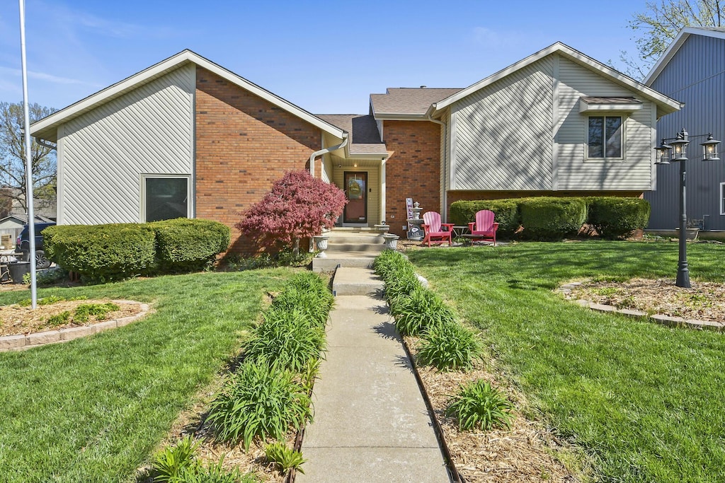 split level home with brick siding and a front lawn