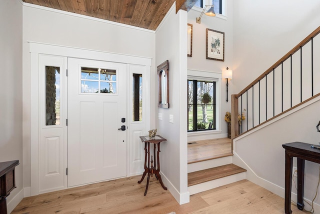 entrance foyer with wood ceiling, stairway, baseboards, and light wood finished floors