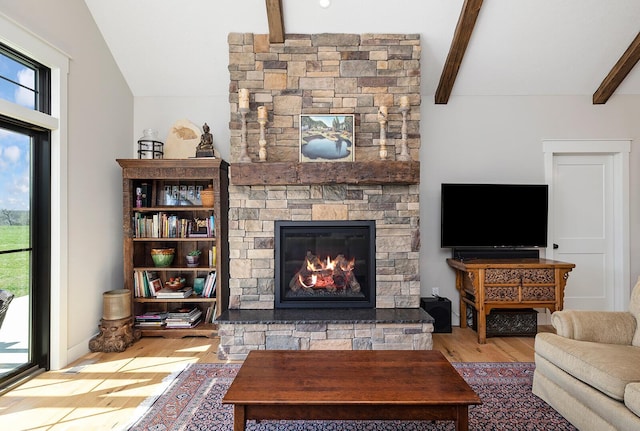 living area with a fireplace, vaulted ceiling with beams, and wood finished floors