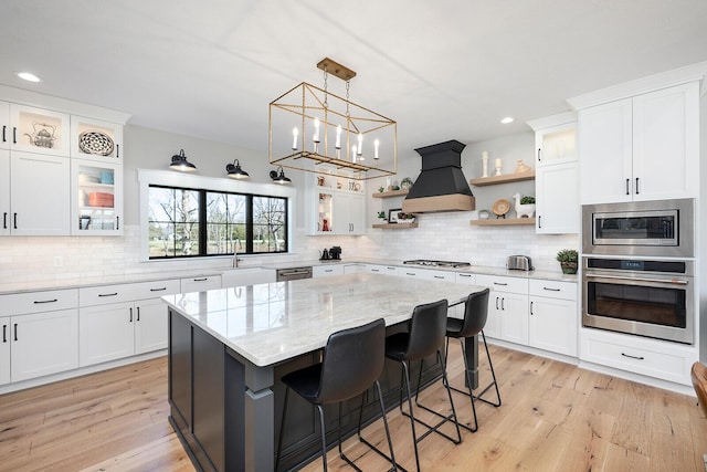 kitchen with tasteful backsplash, open shelves, premium range hood, stainless steel appliances, and light wood-style flooring