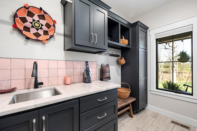 kitchen featuring plenty of natural light, visible vents, a sink, and decorative backsplash