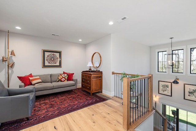 living room with recessed lighting, visible vents, baseboards, and wood finished floors