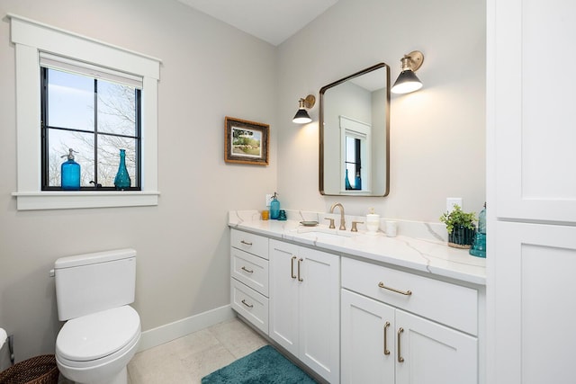 bathroom with toilet, vanity, and baseboards