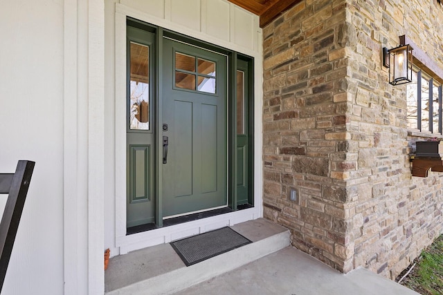 doorway to property featuring a porch, stone siding, and board and batten siding