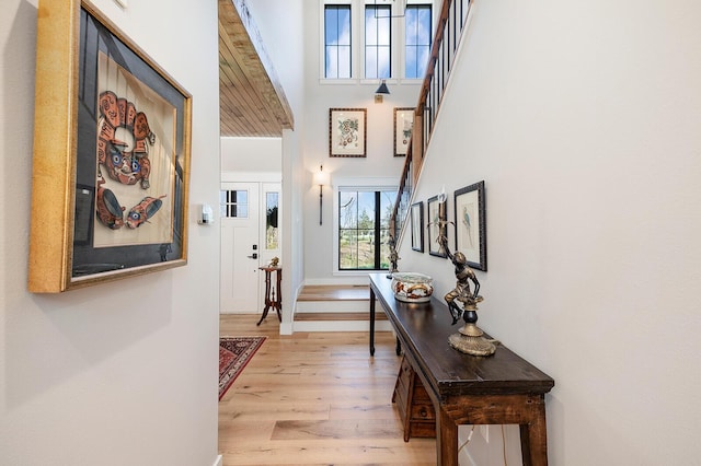 foyer entrance with baseboards, a high ceiling, and light wood-style floors