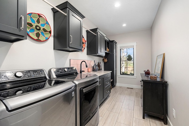 laundry area with recessed lighting, washing machine and clothes dryer, a sink, baseboards, and cabinet space