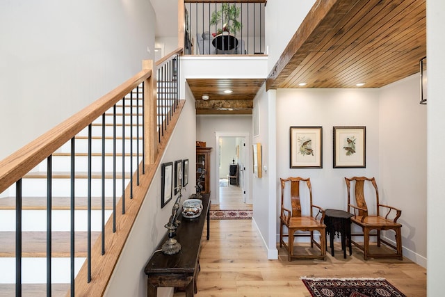 entryway with wood ceiling, wood finished floors, a towering ceiling, and a healthy amount of sunlight