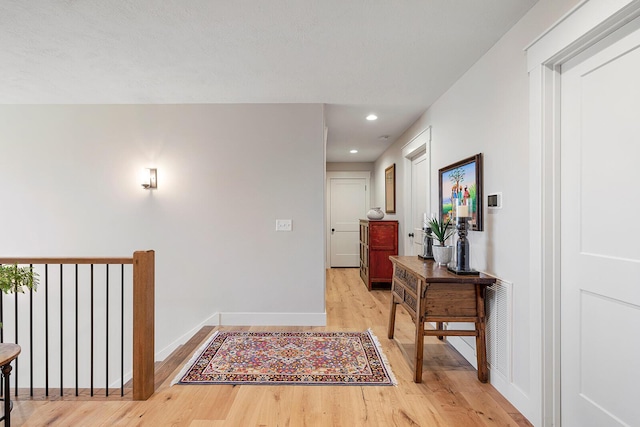 hallway featuring visible vents, baseboards, light wood finished floors, and recessed lighting
