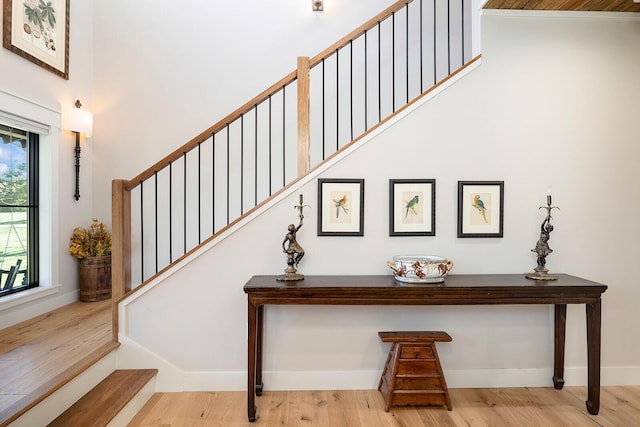 staircase featuring wood finished floors, a high ceiling, and baseboards