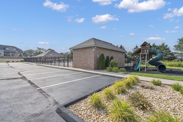 uncovered parking lot featuring playground community and fence