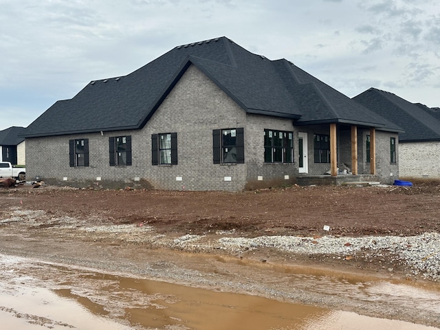 view of side of home with a shingled roof and brick siding