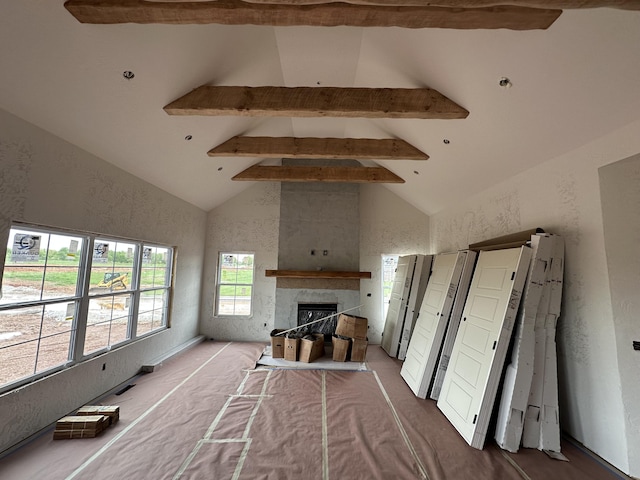 unfurnished living room featuring a textured wall, a fireplace, high vaulted ceiling, and beamed ceiling
