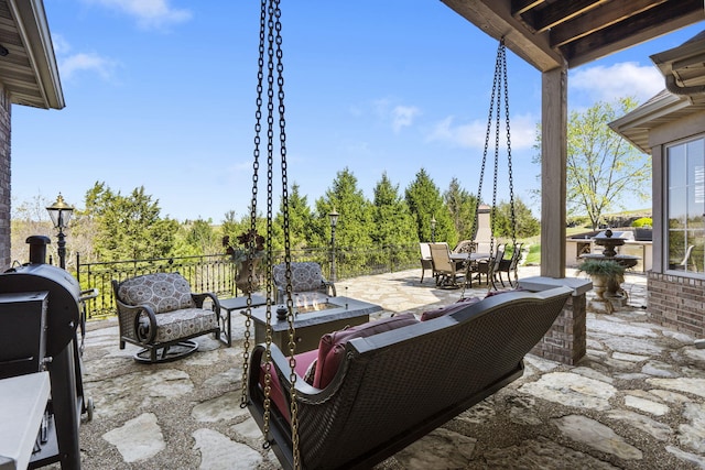 view of patio with an outdoor living space with a fire pit, fence, outdoor dining area, and area for grilling
