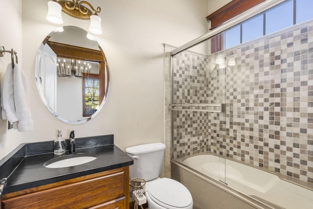 full bath with toilet, a chandelier, vanity, and bath / shower combo with glass door