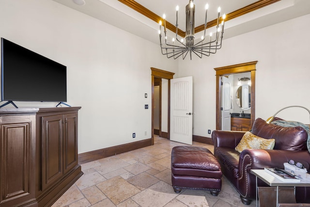living room featuring baseboards, an inviting chandelier, crown molding, stone tile flooring, and a tray ceiling