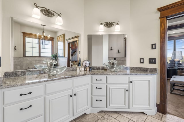 bathroom with ensuite bathroom, double vanity, and a notable chandelier