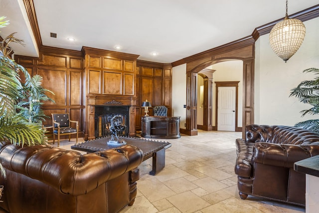 living area featuring ornamental molding, ornate columns, arched walkways, and stone tile floors
