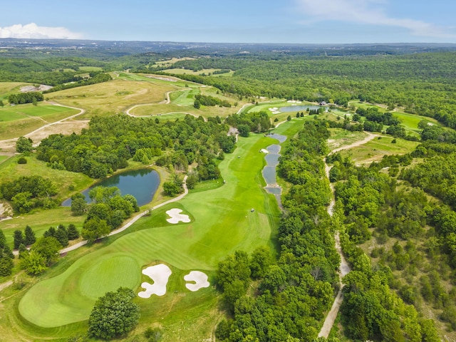 aerial view featuring golf course view, a wooded view, and a water view