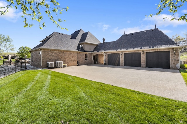 view of side of property featuring a yard, brick siding, an attached garage, a shingled roof, and central AC unit
