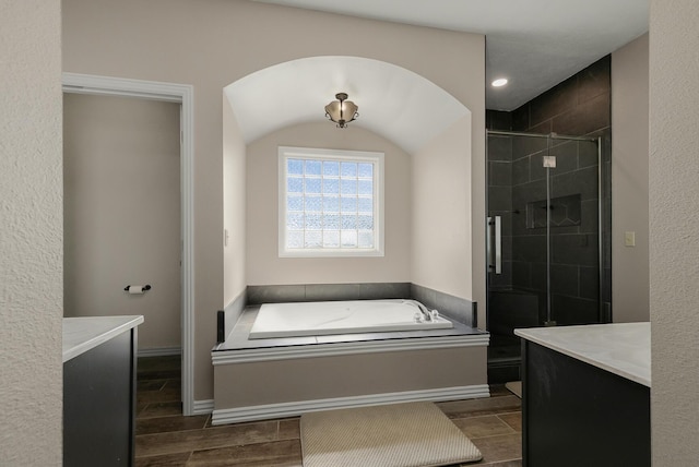 bathroom with a bath, wood finish floors, and a stall shower