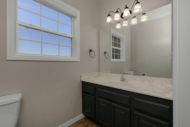 half bathroom featuring toilet, vanity, and baseboards