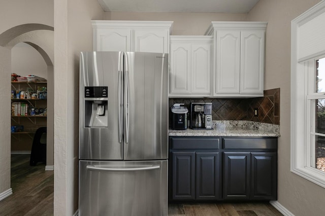 kitchen featuring white cabinets, dark wood finished floors, decorative backsplash, and stainless steel fridge