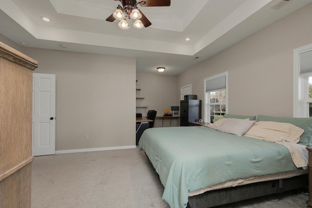 bedroom with visible vents, a tray ceiling, baseboards, and light carpet