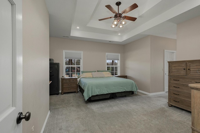 bedroom featuring baseboards, light carpet, a raised ceiling, visible vents, and ceiling fan